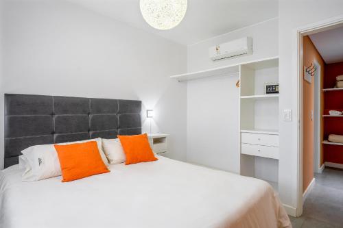 um quarto com uma grande cama branca com almofadas laranja em Departamento Apart Espacio Marina em Villa Gesell