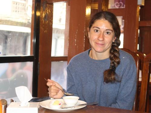 a woman sitting at a table with a plate of food at HOTEL RUPAKOT AND ROOFTOP RESTAURANT in Bhaktapur