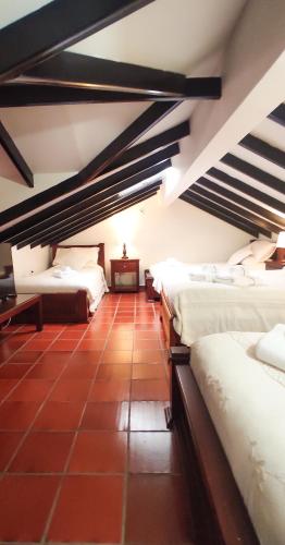 a room with three beds and a red tile floor at Casona 1865 in Ráquira