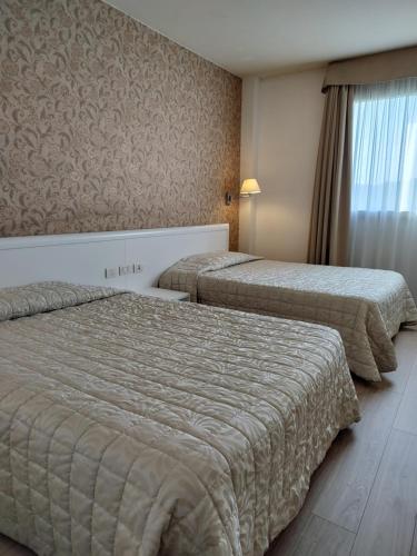 a hotel room with two beds and a window at Hotel Datini in Prato