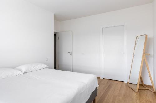 een witte slaapkamer met een bed en een spiegel bij Casa Bassani con terrazzo by Wonderful Italy in Bologna