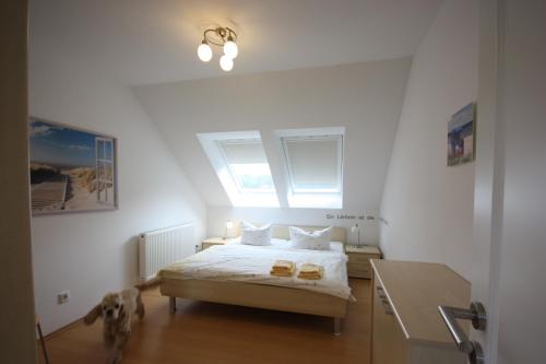 オストゼーバート・コゼロウにあるFerienwohnungen Seevogelのベッドルーム1室(犬が隣に立つベッド1台付)
