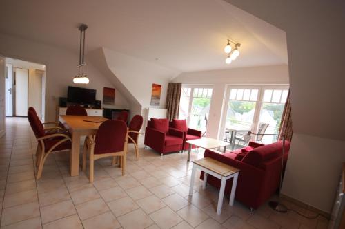 a living room with red chairs and a table at Ferienwohnungen Seevogel in Koserow