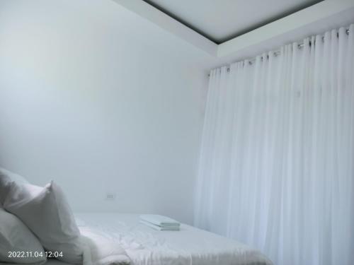 a white bedroom with a bed and a window at CHIEF'S VILLA Rentals Malapascua Island in Malapascua Island