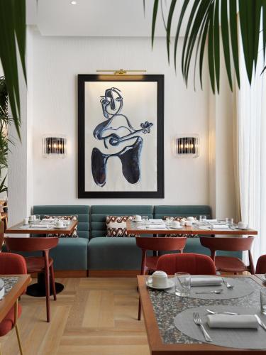 a dining room with a blue couch and a picture of a guitar at H10 Croma Málaga in Málaga