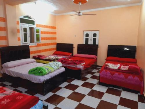 a room with three beds and a checkered floor at Algaafary GeustHouse in Aswan