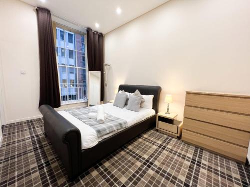 a bedroom with a bed and a large window at Queen Street City Centre Apartment in Glasgow