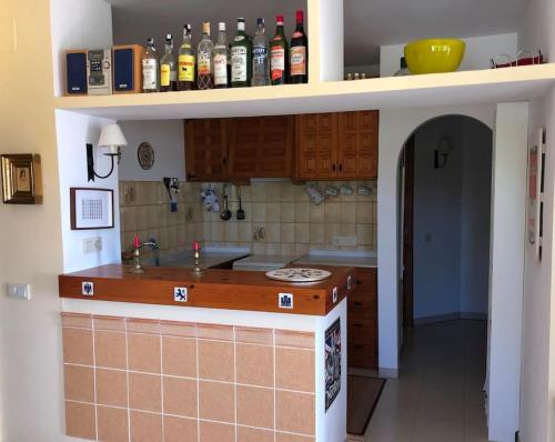 a kitchen with a counter with bottles on the wall at Casa Peppino in Teulada