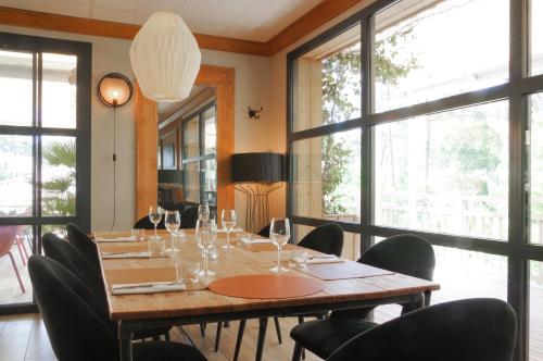 a dining room with a table and chairs and windows at Domaine du Ferret Restaurant & Spa in Cap-Ferret
