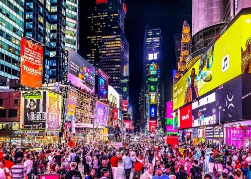 a crowd of people walking down a busy city street at night at Nap York Central Park Sleep Station in New York