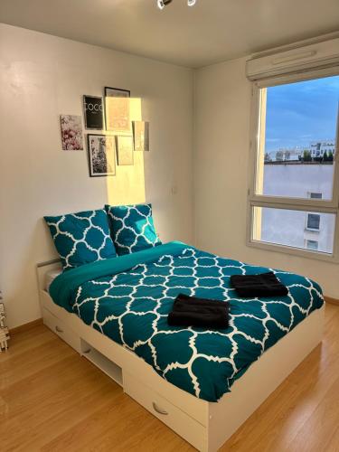 une chambre avec un lit avec une couette bleue et une fenêtre dans l'établissement Cosy appartement with free parking a Paris, à Villejuif