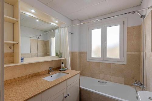 a bathroom with a sink and a tub and a mirror at 797 Holiday Rentals - Elegante apartamento para 2 en Torremolinos. in Torremolinos