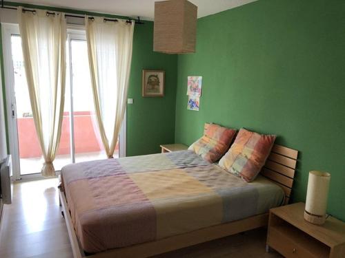 - une chambre avec des murs verts et un lit avec des oreillers colorés dans l'établissement Appartement T3 - Face à l'océan - Idéal famille - Terrasse - Vieux-Boucau-les-Bains - FR-1-379-88, à Vieux-Boucau-les-Bains