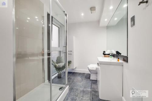 a bathroom with a shower and a toilet and a sink at Stylish Three Bedroom Apartment by London ExCeL in London