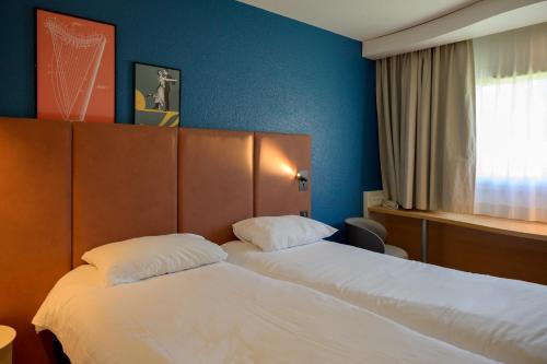 a hotel room with two beds and a window at ibis Aix en Provence in Aix-en-Provence