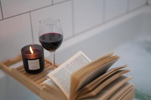 a book and a candle and a glass of wine at Saltbox Stays- 3 bed house with off-street parking, sleeps 6 in Newhall