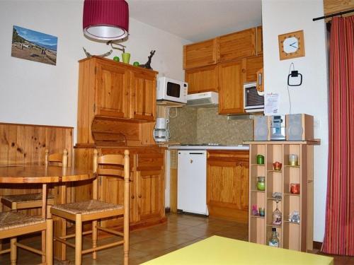 a kitchen with wooden cabinets and a table and a table and chairs at Appartement calme centre station avec parking - FR-1-593-41 in Les Angles
