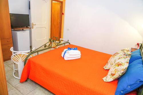a bedroom with an orange bed with towels on it at B&B La Strea in Porto Cesareo