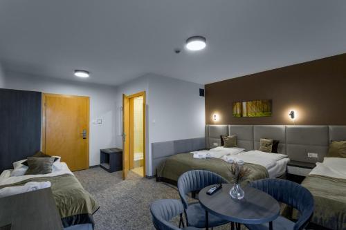 a hotel room with two beds and a table and chairs at Pensjonat Śnieżka SPA in Karpacz