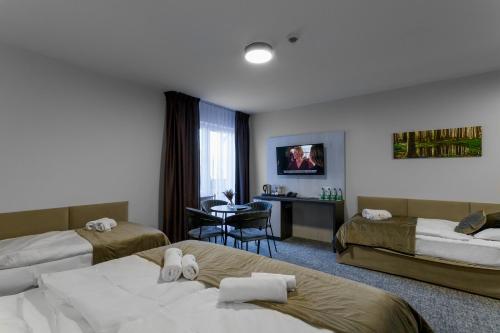 a hotel room with two beds and a table at Pensjonat Śnieżka SPA in Karpacz