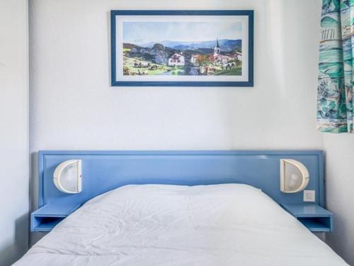 a bed with a blue headboard and a picture on the wall at Appartement Urrugne, 2 pièces, 4 personnes - FR-1-4-567 in Urrugne