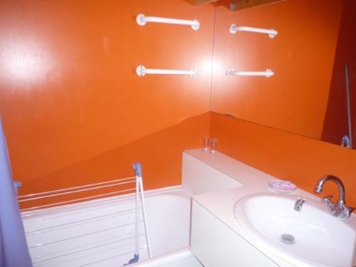 La salle de bains orange est pourvue d'un lavabo et d'un miroir. dans l'établissement Studio 4 pers, balcon sud-ouest, proche pistes et commerces, Arc 1800 - FR-1-411-642, à Arc 1800