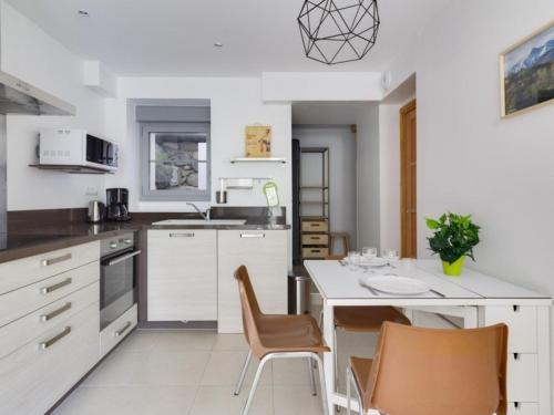 une cuisine avec des armoires blanches et une table et des chaises dans l'établissement Studio centre-ville avec terrasse, parking, proche télécabine et commodités - FR-1-401-175, à Cauterets
