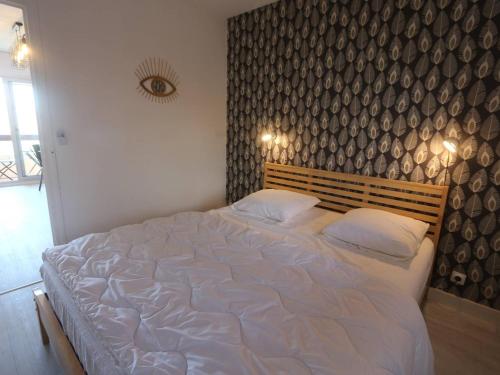 a large white bed in a bedroom with a wall at Appartement T2 à Bénodet, refait à neuf, balcon, plage à pied, parking, classé 2 étoiles - FR-1-481-64 in Bénodet