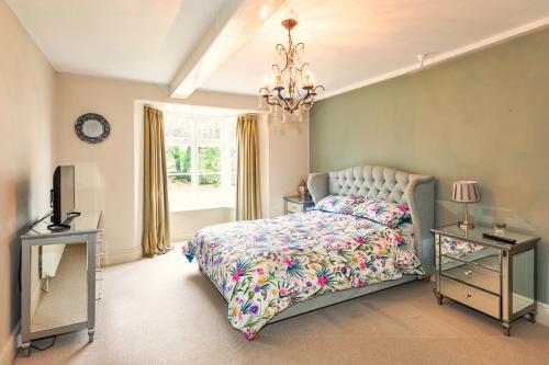 a bedroom with a bed and a chandelier at Finest Retreats - Islip Mill House - Beautiful Riverside Home in Islip