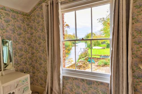 a room with a window with a view of the water at Finest Retreats - Islip Mill House - Beautiful Riverside Home in Islip