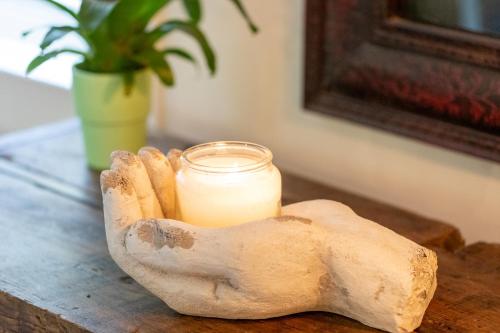 a candle in a hand with a candle holder on a table at Finest Retreats - Islip Mill House - Beautiful Riverside Home in Islip