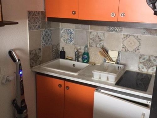 une cuisine avec un évier blanc et des armoires orange dans l'établissement Studio confortable pour 4 avec ascenseur et balcon à Arette - FR-1-602-96, à Arette