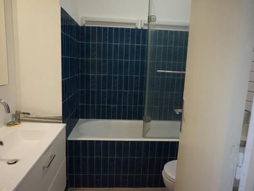 a bathroom with a tub and a toilet and blue tiles at Appartement Cabourg, 2 pièces, 4 personnes - FR-1-465-61 in Cabourg