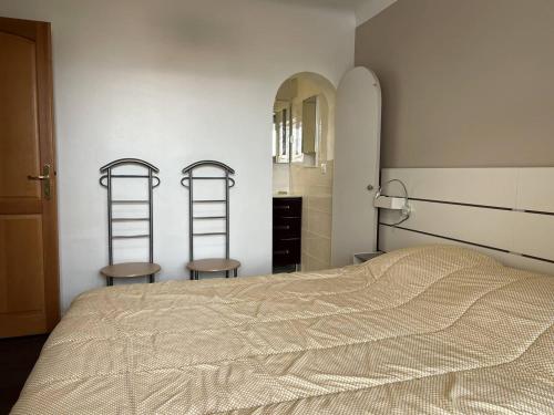 - une chambre avec un lit, deux chaises et un miroir dans l'établissement Charmant T1 bis avec terrasse et parking, à 1km des thermes, idéal pour 2 pers, Wi-Fi, Cambo-les-Bains - FR-1-495-90, à Cambo-les-Bains