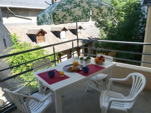 une table et des chaises blanches sur un balcon avec un parasol dans l'établissement Luchon: Appartement 2 chambres proche thermes, balcon, parking, WiFi - Animaux <10kg acceptés - FR-1-313-186, à Luchon