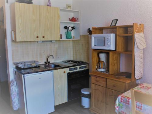 Il comprend une petite cuisine équipée d'un réfrigérateur blanc et d'un four micro-ondes. dans l'établissement Studio calme pour 4 pers. à Risoul, proche pistes, animaux admis, parking gratuit - FR-1-330-512, à Risoul