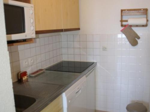 - une cuisine avec un comptoir et un four micro-ondes dans l'établissement 3 pièces au pied des pistes avec balcon et coin cuisine équipé - FR-1-557-33, à Les Adrets