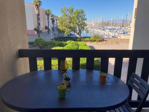 une table bleue avec deux tasses et une lampe sur un balcon dans l'établissement Appartement 2 pièces climatisé, parking privé, proche plage - FR-1-81-535, à Port-Leucate
