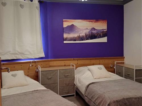 a bedroom with two beds and a purple wall at Bel appartement 6/8 pers avec balcon, au cœur de Val Thorens - FR-1-545-21 in Val Thorens