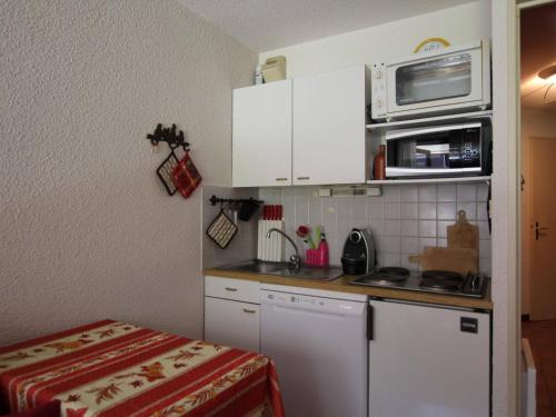une petite cuisine avec des armoires blanches et un micro-ondes dans l'établissement Montgenèvre : Duplex 6 pers, skis aux pieds, proche centre, vue ouest, parking inclus, animaux acceptés - FR-1-330D-113, à Montgenèvre