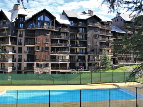 - un grand bâtiment avec un court de tennis en face dans l'établissement Studio cabine avec accès direct aux pistes, balcon, et piscine - 4 couchages, Risoul 1850 - FR-1-330-518, à Risoul