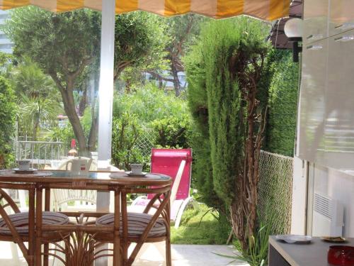 une table et des chaises sur une terrasse avec une haie dans l'établissement Charmant studio en RDJ, terrasse, jardin, proche mer et commerces, plein sud, 2 couchages - FR-1-252A-49, à Villeneuve-Loubet