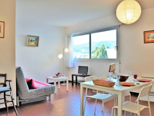un salon avec une table et des chaises et une fenêtre dans l'établissement Appartement 2 pièces avec piscine et parking à 2 pas de la plage au Lavandou - FR-1-251-384, au Lavandou