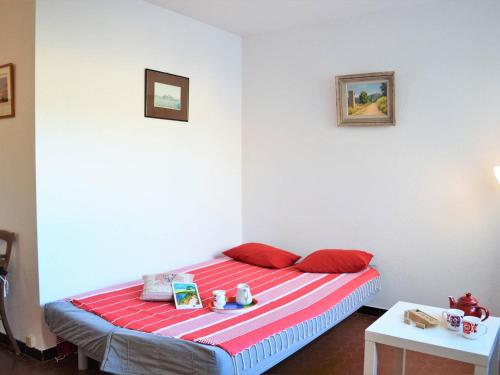 Cette chambre comprend un lit avec des oreillers rouges et 2 tables. dans l'établissement Appartement 2 pièces avec piscine et parking à 2 pas de la plage au Lavandou - FR-1-251-384, au Lavandou