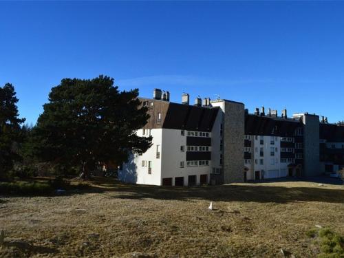 un grand bâtiment blanc avec un arbre devant dans l'établissement Appartement cosy 2 pièces cabine, proche commerces et pistes, 6 pers, animaux OK - FR-1-592-20, à Bolquère-Pyrénées 2000