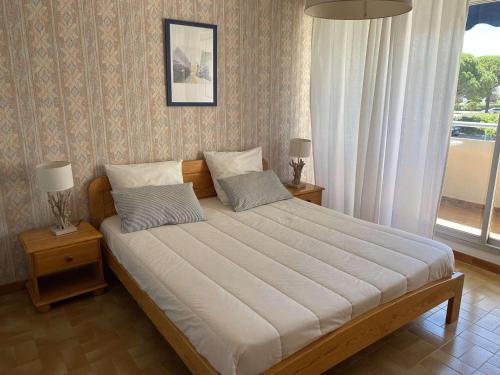 - une chambre avec un grand lit, deux lampes et une fenêtre dans l'établissement Appartement 2 pièces avec parking à Port Camargue - FR-1-250-170, au Grau-du-Roi