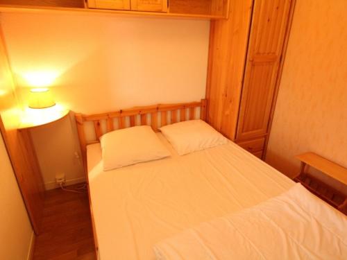 a small bedroom with a white bed and a lamp at Appartement Bagnères-de-Luchon, 2 pièces, 4 personnes - FR-1-313-170 in Luchon
