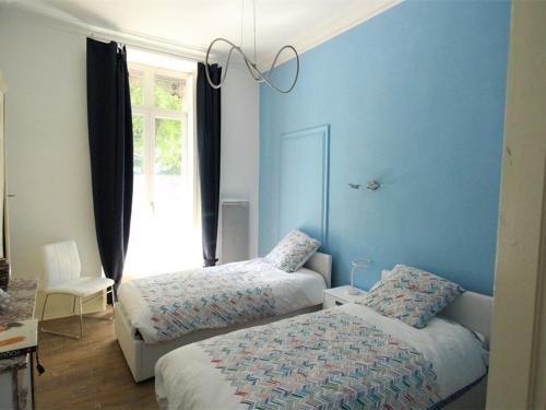 Cette chambre comprend 2 lits dans une chambre dotée de murs bleus et d'une fenêtre. dans l'établissement Luxueux T3 Centre-Ville, 4 Pers, Proche Thermes et Télécabine - FR-1-313-172, à Luchon