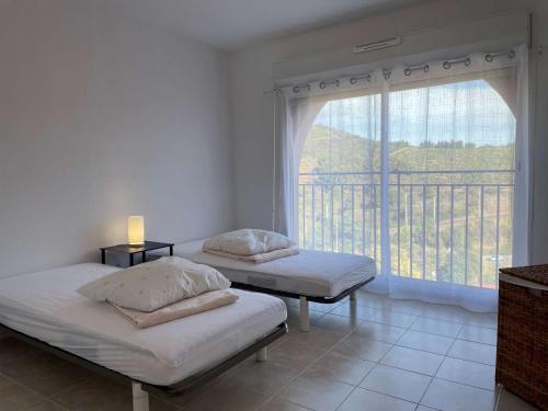 deux lits dans une chambre avec une grande fenêtre dans l'établissement Maison 2 chambres avec garage, proche plage des Elmes - FR-1-225C-88, à Banyuls-sur-Mer