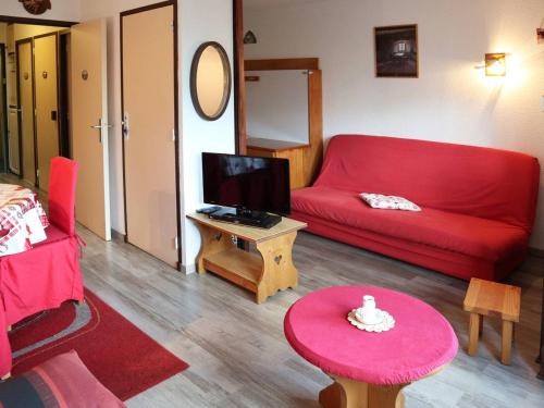 un salon avec un canapé rouge et une table dans l'établissement Studio prestige 4 pers, skis aux pieds, cheminée, balcon, sans animaux, wifi libre - FR-1-322-441, aux Orres
